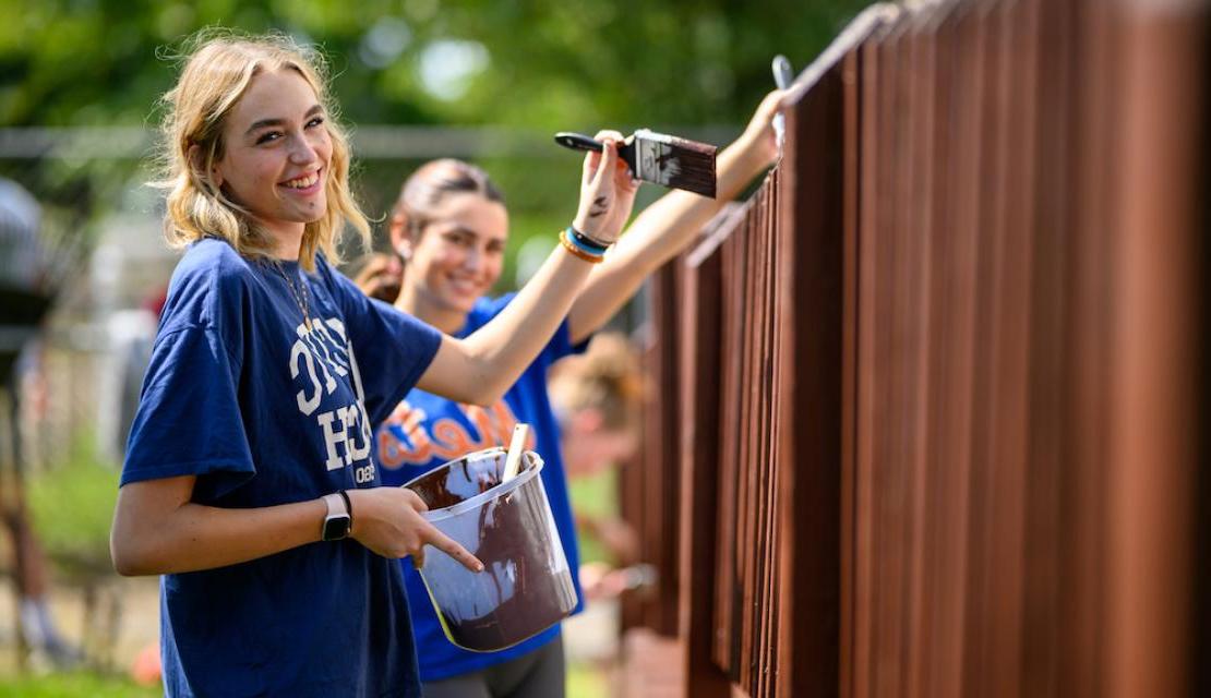 作为“人文行动”的一部分，学生志愿者们正在粉刷栅栏