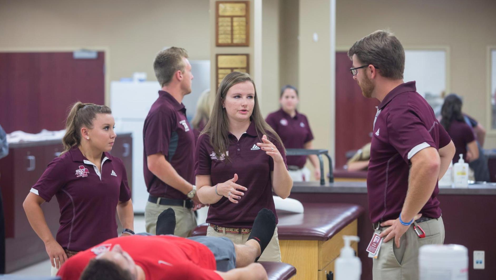 Athletic training students have a discussion about a client in the athletic training facility.