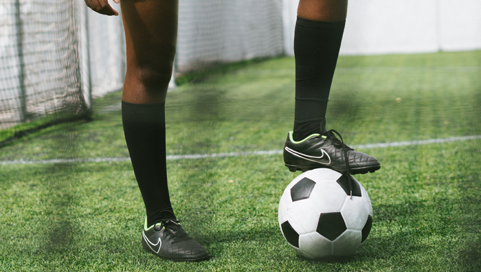 一名年轻女子足球运动员的脚放在足球上